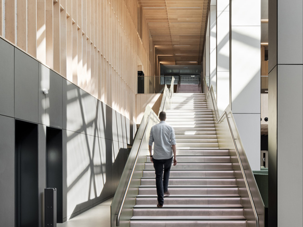 Man walking up illuminated staircase at University of Wolverhampton's SoABE building